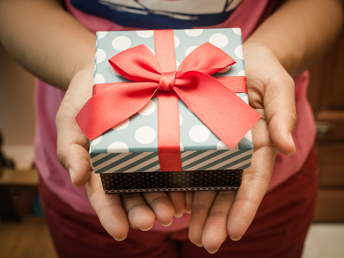 Woman holding a gift box in a gesture of giving