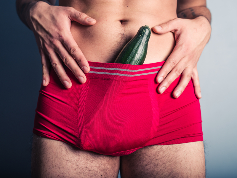 A young man has stuffed a large cucumber down his underpants