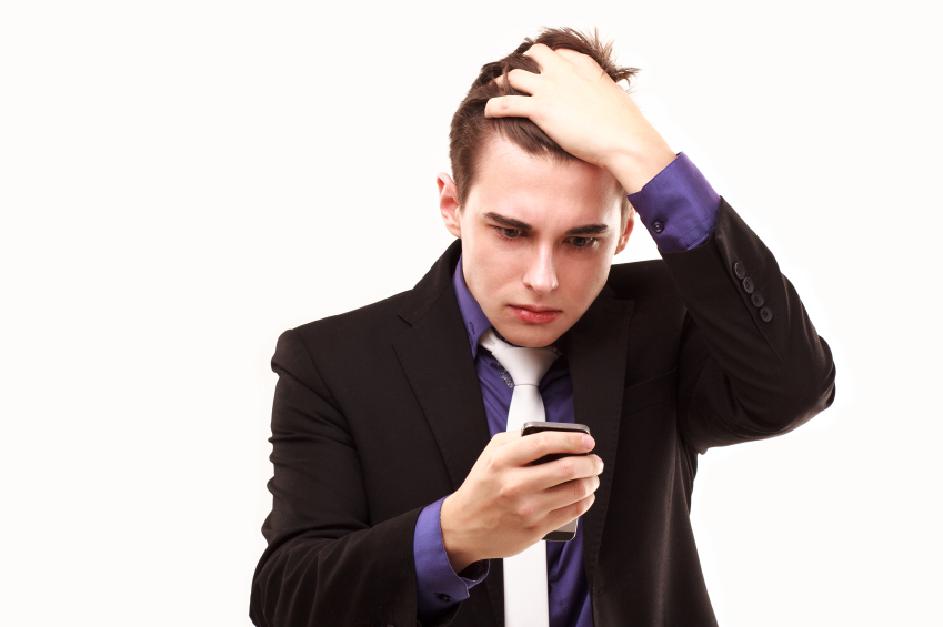 Young stressed man in suit looking at a mobile phone